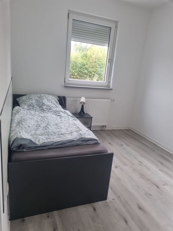 Einzelbett mit Nachttisch und Leselampe unter dem Fenster